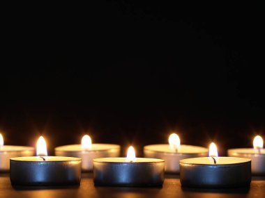 Arka planı bulanık, siyah bir masada sarı alevli mumlar yakmak. Noel mumları. Geceleri kilisede mum yakardı.