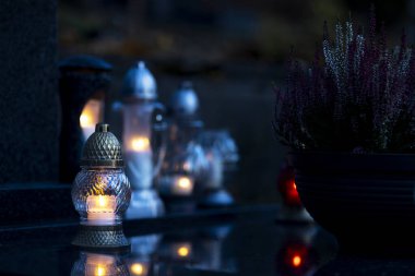 Mezarlıktaki siyah taş anıtın üzerinde geceleri yanan bir mum. Merhumun anıları. Aşkın ifadesi