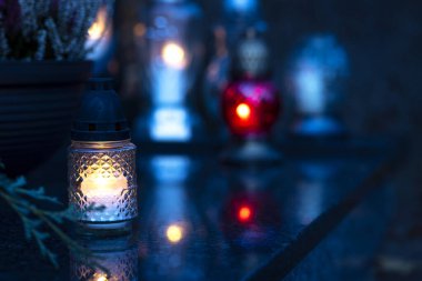 Mezarlıktaki siyah taş anıtın üzerinde geceleri yanan bir mum. Merhumun anıları. Aşkın ifadesi