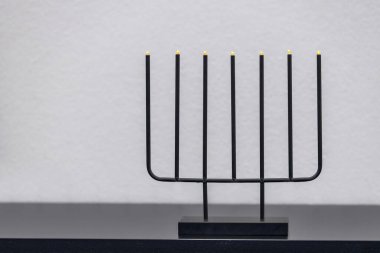 Siyah siyah bir rafta modern siyah çelik şamdan ve elektrik ampulleri.