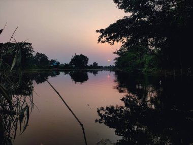 Öğleden sonra, kuzey Hindistan 'da küçük bir nehir kıyısında harika bir güneş batar..