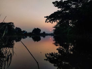 Öğleden sonra, kuzey Hindistan 'da küçük bir nehir kıyısında harika bir güneş batar..