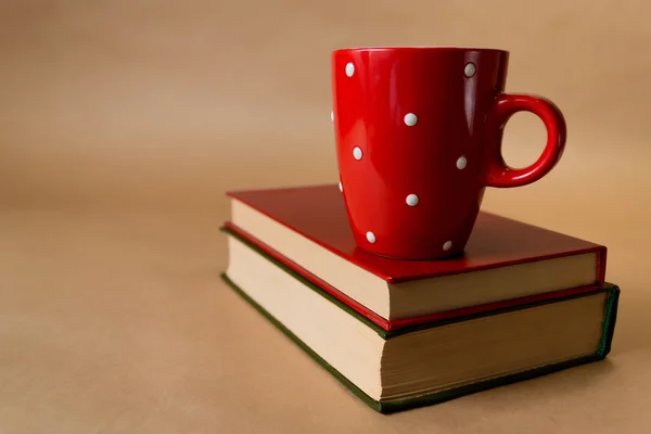 İki kitabı ve kahverengi zemin üzerine kırmızı Kupası