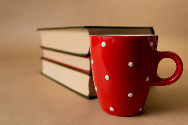 Üç kitap ve kahverengi zemin üzerine kırmızı Kupası