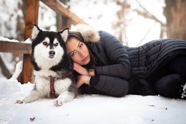 Güzel genç bir kadın soğuk kış gününde dişi köpeğe sarılıyor.