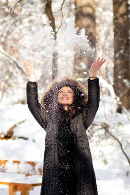 Karlı ormanda kar topu atan bir kadın eğleniyor..