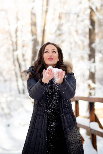 雪を投げ、雪の森で楽しむ若い女性. — ストック写真