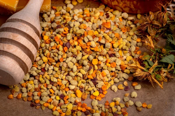 Arı poleni, arı cilası, kurumuş çiçekler ve arka planda bal.
