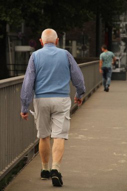Parkta yürüyen yaşlı insanlar.