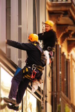 Yükseklikteki temizleyiciler emniyet kemerleriyle çalışıyorlar