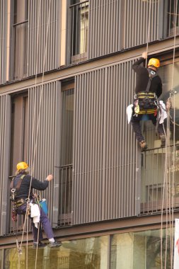 Yükseklikteki temizleyiciler emniyet kemerleriyle çalışıyorlar