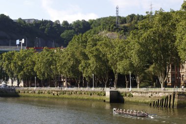 Bir kürek yarışması sırasında nehir kenarındaki insanlar