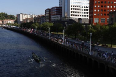 Bir kürek yarışması sırasında nehir kenarındaki insanlar