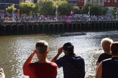 Bir kürek yarışması sırasında nehir kenarındaki insanlar