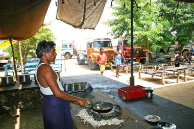 Kerala,India - July 13, 2004: Old man preparing food on the roadside eatery place in the middle of highways, Kerala.