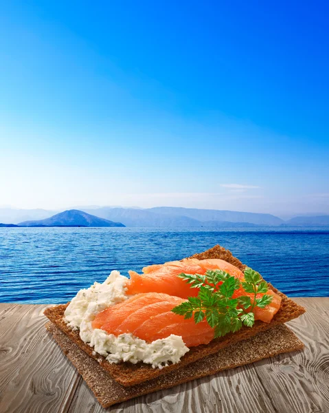 Bread crisp with salmon, rustic table, seascape — Stock Photo, Image