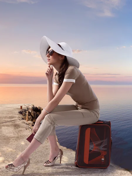 Traveling woman sitting on her luggage