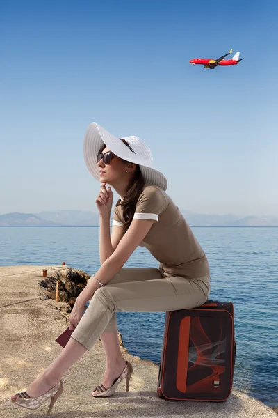 Traveling woman sitting on her luggage — Stock Photo, Image