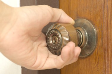 Closeup of male hand opening an old door knob clipart