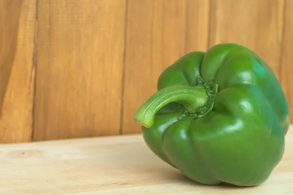 Solo pimiento verde sobre mesa de madera y fondo de madera marrón — Foto de Stock