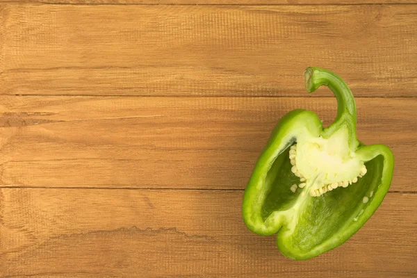 Cross section of single green bell pepper with wooden background — Stock Photo, Image