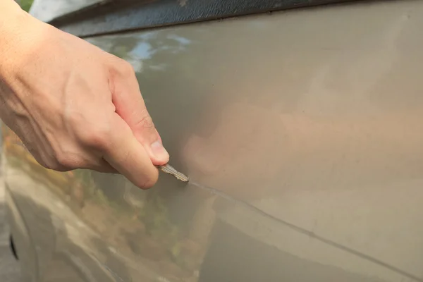 Mannenhand krassen van een auto met behulp van zilveren sleutel Stockfoto