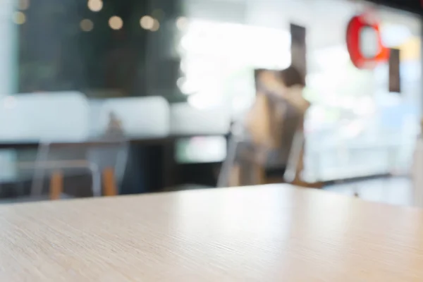 Abstract blurry coffee shop counter with wooden table in foreground background