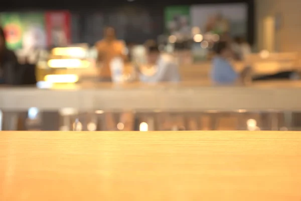 Abstract blurry coffee shop counter with wooden table in foreground background — Stockfoto