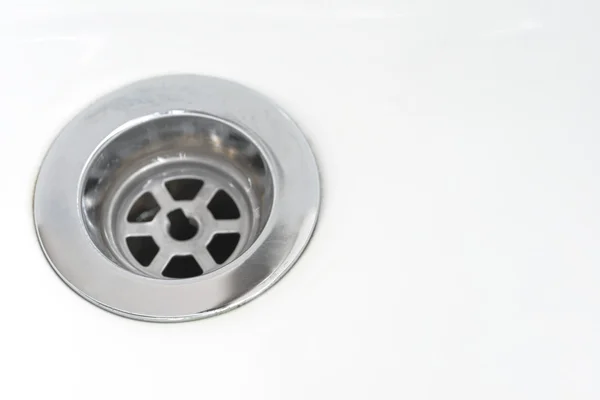 Closeup of stainless steel drain of white washbasin background — Stock Photo, Image