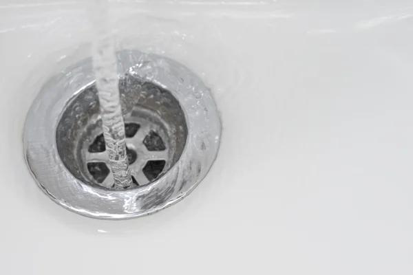 Arka plan beyaz lavabo paslanmaz çelik drenaj akan su dokunun closeup
