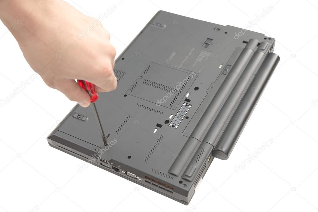 Male hand turning screw under laptop bottom isolated on white
