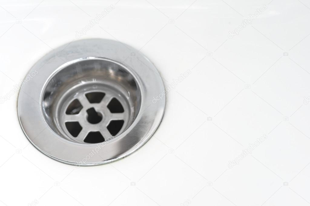 Closeup of stainless steel drain of white washbasin background