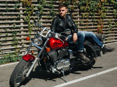 Klasik bir motosikletin üstünde oturan genç bir motosikletçi.