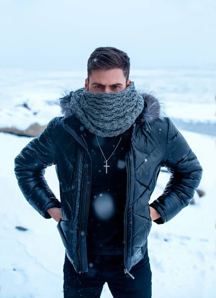Um homem no inverno em um fundo de neve em roupas pretas — Fotografia de Stock