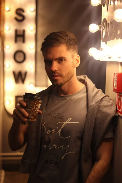 Um cara com um café na mão olha para a câmera — Fotografia de Stock