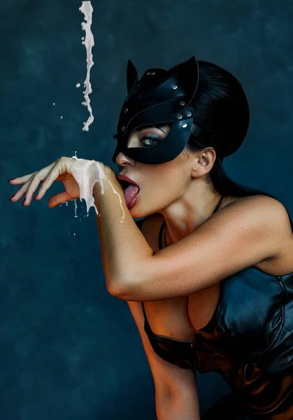 Сексуальная девушка в кожаной маске bdsm кошки облизывает молоко — стоковое фото
