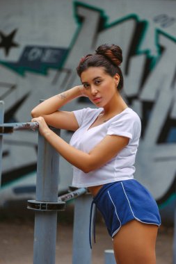 Oyun alanında eşofmanlı esmer bir kadın fotoğraf çekimi için poz veriyor.