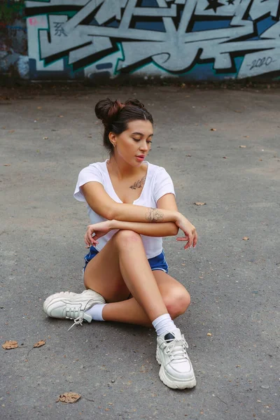 Bruna seduta sull'asfalto, sullo sfondo — Foto Stock