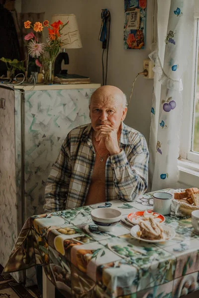 Русский дедушка сидит в рубашке за столом — стоковое фото
