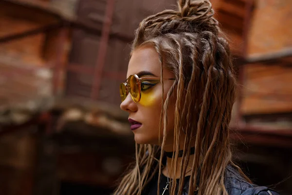Жінка з дредлоками зачіска і жовті окуляри під час ходьби в місті . — стокове фото