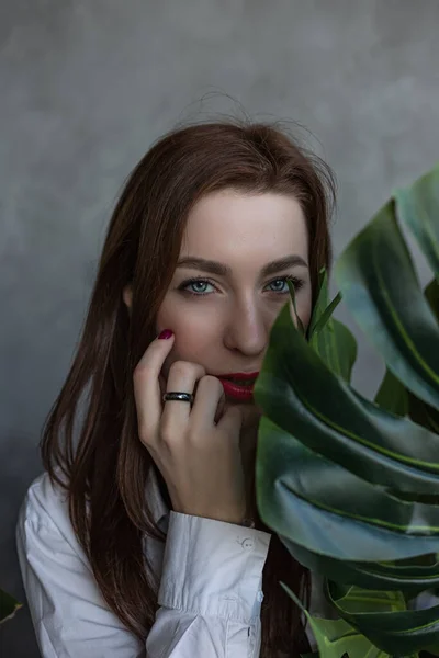 Bellezza Giovane donna naturale nasconde i suoi occhi dietro una foglia verde fresca durante l'invio. Primo piano ritratto contro — Foto Stock
