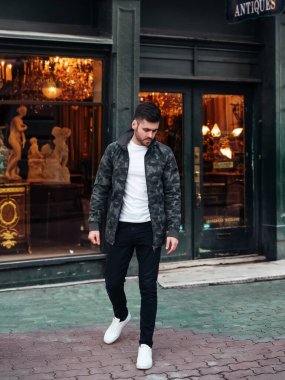 Deri ceketli, kirli sakallı, kahverengi gözlü vahşi bir adam.