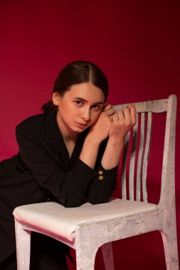 Kırmızı arka planda siyah ceketli bir kız.