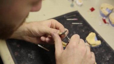 Diş teknisyeni laboratuardaki diş implantları için 3D baskı kalıbı üzerinde çalışıyor.