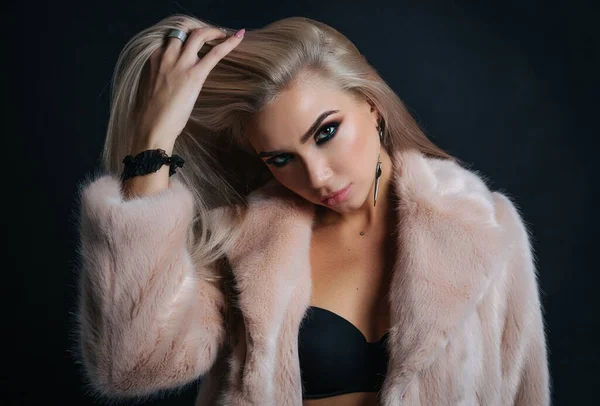 Portrait of a young woman in a fur coat with beautiful professional makeup on a dark background, — Stock Photo, Image