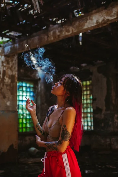 Dívka kráčí ulicí, kouří cigaretu, s obarvenými vlasy — Stock fotografie