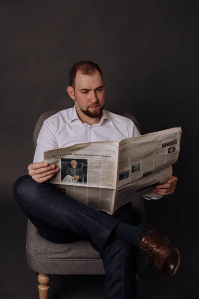 Um homem lê um jornal sentado na cruz, ao fundo — Fotografia de Stock