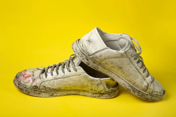 Chaussures sales, baskets blanches déchirées vintage isolées sur fond jaune. — Photo
