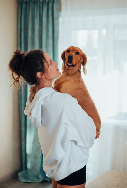 Menina em casa roupas segurando um cão em seus braços — Fotografia de Stock