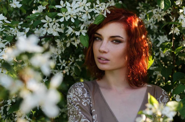 Retrato de una niña pelirroja con pecas en un manzano en flor, al atardecer, primavera —  Fotos de Stock